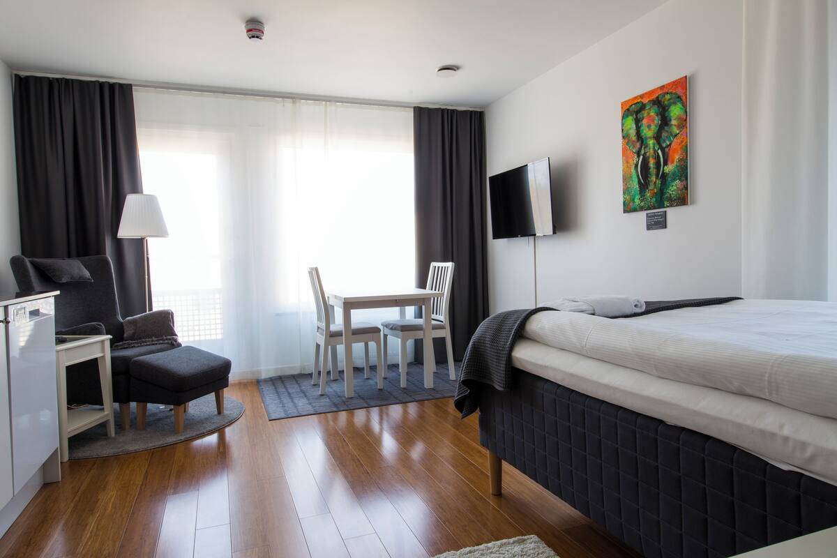 Ein modernes Hotelzimmer mit Bett, Schreibtisch, Stuhl, Fernseher und einem Bild an der Wand.