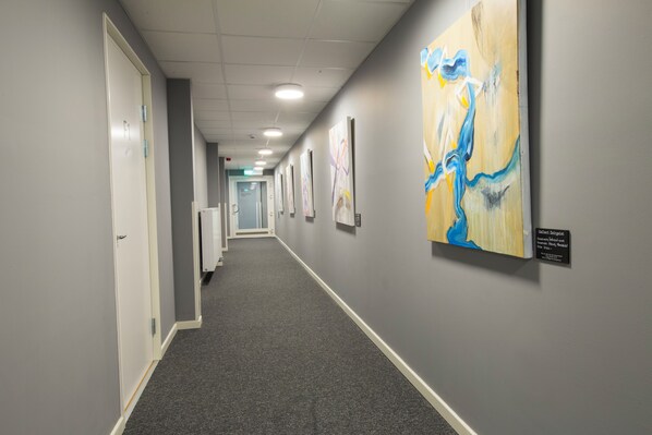 A hallway with grey walls, a carpeted floor, and several doors. - Continental Apartment Hotels Sollentuna (Sollentuna)