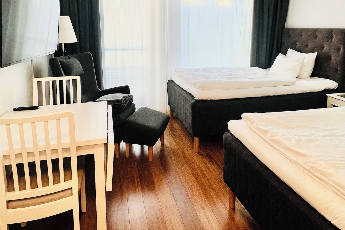 Ein Hotelzimmer mit einem Bett, einem Schreibtisch mit Stuhl, einem kleinen Tisch und einem Fernseher.