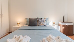 Une chambre à coucher comprenant un lit, deux tables de chevet, une commode, un meuble en bois et deux lampes.