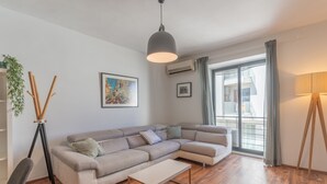Un salon moderne avec un canapé d’angle, une petite table et une lampe sur pied.