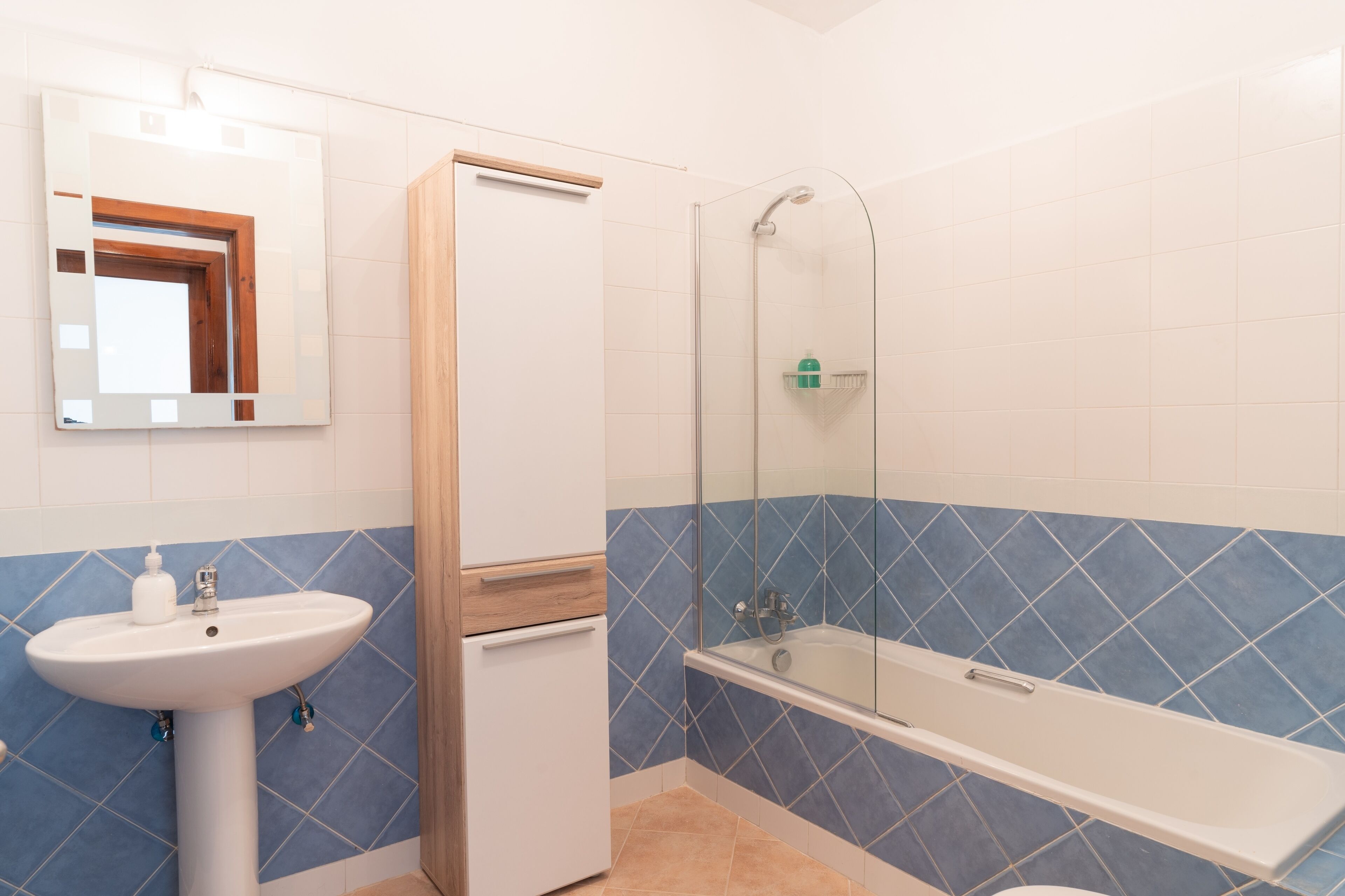 A bathroom with a sink, mirror, shower, and bathtub.