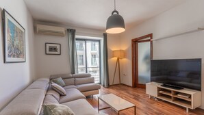 Un salon moderne avec un canapé, un téléviseur et une lampe.