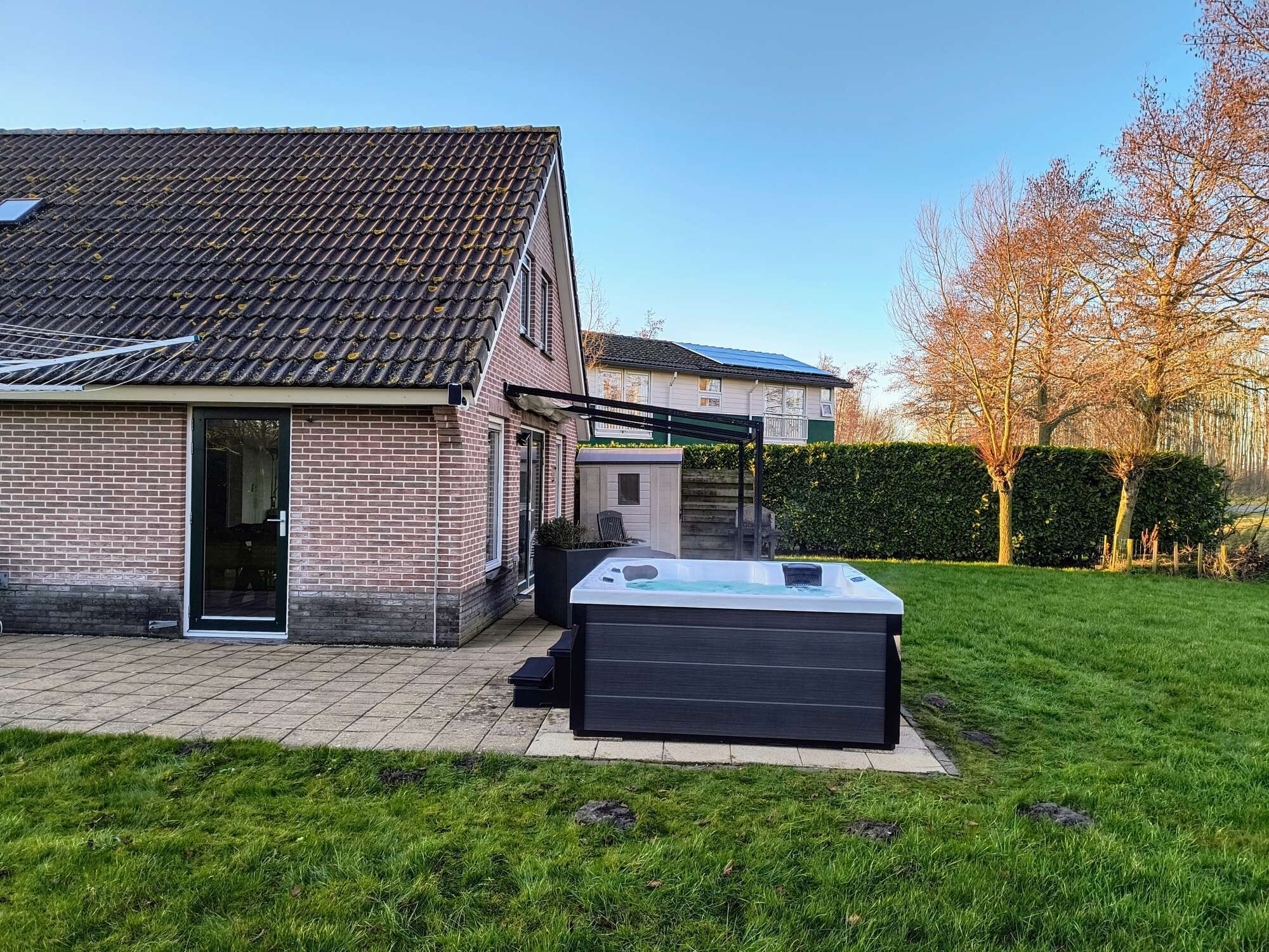A house with a tiled roof, a brick exterior, and a patio area with a hot tub.