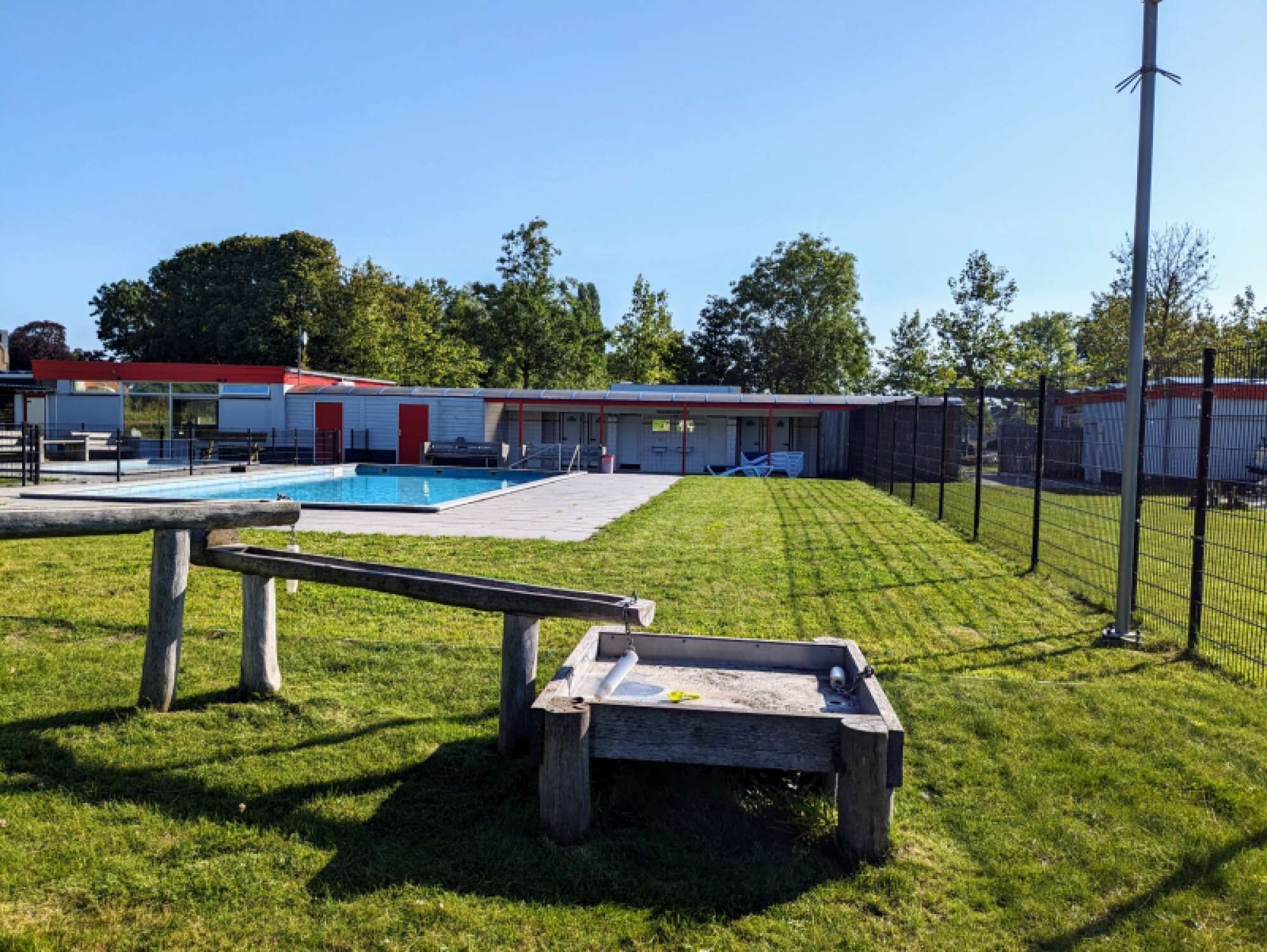 A pool area with a rectangular pool, a wooden deck, and a fenced yard.