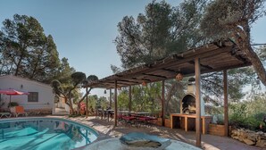 Un área de piscina con un pérgola, asientos exteriores y una mesa de piedra.