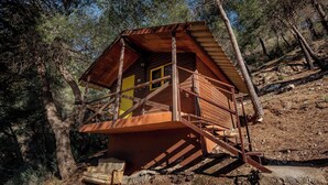Una cabaña rústica con fachada de madera, un balcón y una escalera que conduce a la entrada.