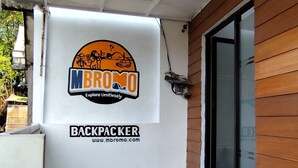 A building exterior with a large outdoor area, a wooden wall, and a glass door. - Malang And Bromo Tour Backpacker (Malang)