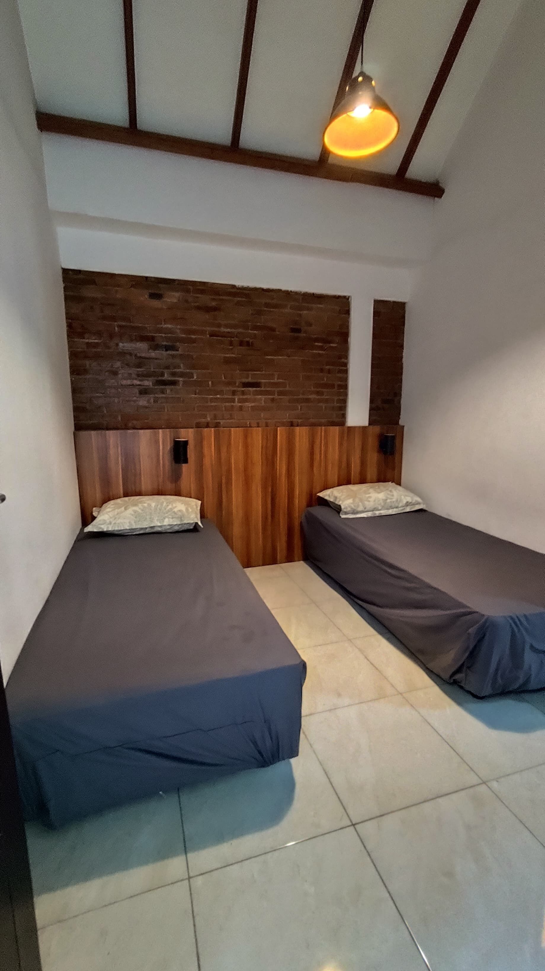 Una habitación con dos camas, un cabecero de madera y una lámpara colgante.