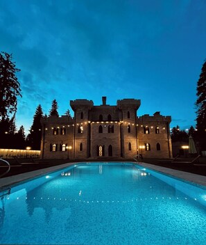 Um edifício com estilo de castelo e uma piscina em frente.