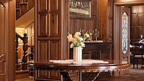 A wooden-paneled room with a chandelier, a table with a vase of flowers, and a painting on the wall. - The Castle - Your unique way of retreat (Samokov)
