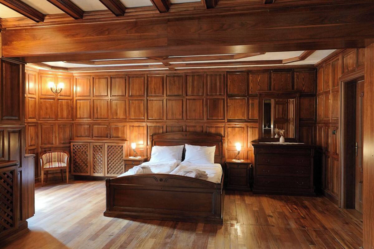 A bedroom with a large wooden bed, built-in wardrobes, and a wooden floor.