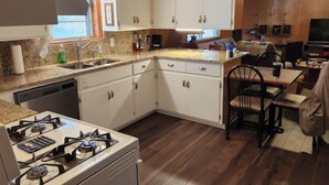 A compact kitchen with white cabinets, a gas stove, and a dishwasher. - Skyline Lodge 
Lake Dardanelle 
Arkansas River Valley (Russellville)