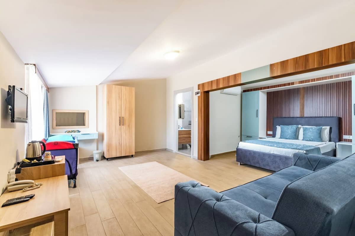 Una camera d'albergo moderna con un letto, una poltrona, una scrivania e un armadio.