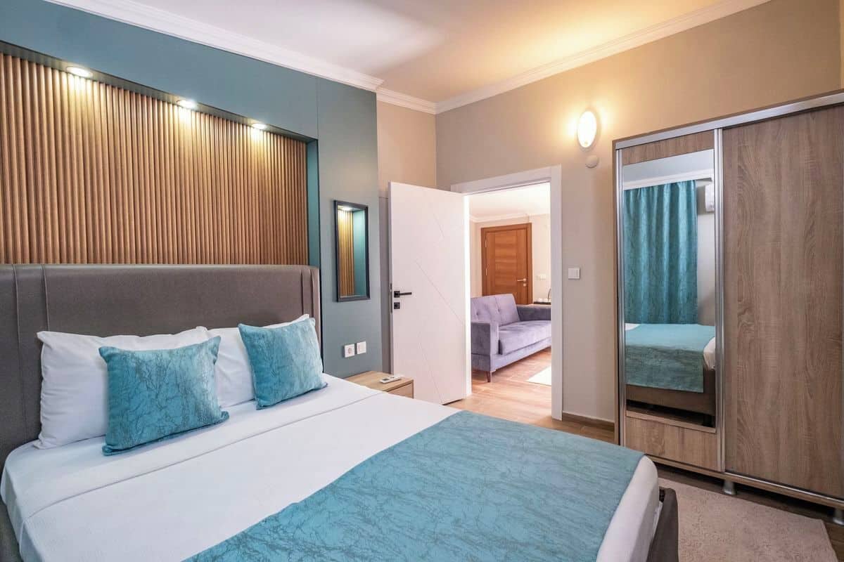 Una camera d'albergo moderna con un letto grande, un armadio e una porta che conduce a un'altra stanza.