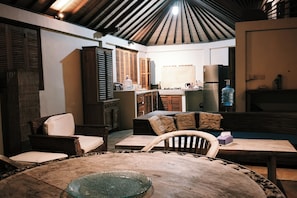 A cozy living area with a dining table, chairs, a sofa, and a kitchen in the background.
