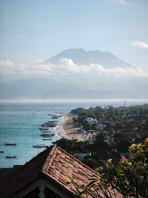 A coastal town with a mountain in the background, boats on the water, and buildings along the shore.