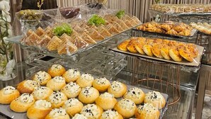 Un buffet proposant une variété de produits de boulangerie, notamment du pain, des viennoiseries et des petits pains, présentés sur des étagères en verre.