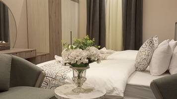 Ein Hotelzimmer mit Bett, Sessel, Nachttisch, Spiegel und Blumenvase.
