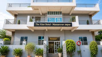 Un hotel moderno con una estructura de dos pisos, una entrada destacada y un letrero que indica que es 'The Nine Hotel - Mansarovar Jaipur'.