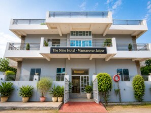 Un hotel moderno con una estructura de dos pisos, una entrada destacada y un letrero que indica que es 'The Nine Hotel - Mansarovar Jaipur'.