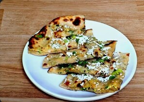A plate of flatbreads with toppings on a wooden table. - The Nine Hotel - Mansarover (Jaipur)