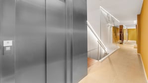 A modern interior with a central elevator, a staircase with glass railings, and a carpeted floor. - Dunes Paradise Suite (Marbella)