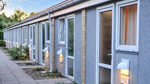 A row of modern, single-story buildings with large windows and small steps leading to the entrance. - Holiday Home With Relaxing Garden (Nexø)