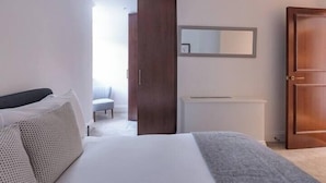 A bedroom with a bed, a wardrobe, a mirror, and a radiator. - Modern, Luxurious 1BR Flat- Heart of Covent Garden (London)
