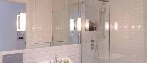 A modern bathroom with a white sink, a glass shower enclosure, and a large mirror.