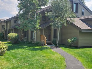 A row of townhouses with a front porch, a pathway leading to the entrance, and a well-maintained lawn.