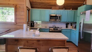 A kitchen with teal cabinets, stainless steel appliances, and a marble countertop. - Snowcreek Resort Vacation Rental 265 (Mammoth Lakes)