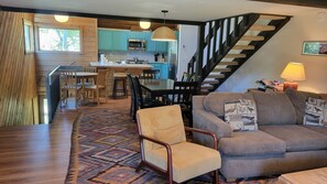 A modern kitchen with a dining area, a staircase, and a living room with a sofa and a patterned rug. - Snowcreek Resort Vacation Rental 265 (Mammoth Lakes)