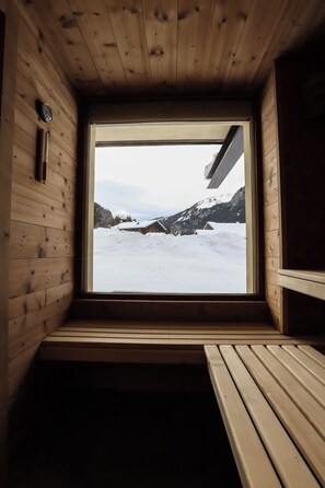 Una cabaña de madera con un amplio ventanal que da a un paisaje nevado.