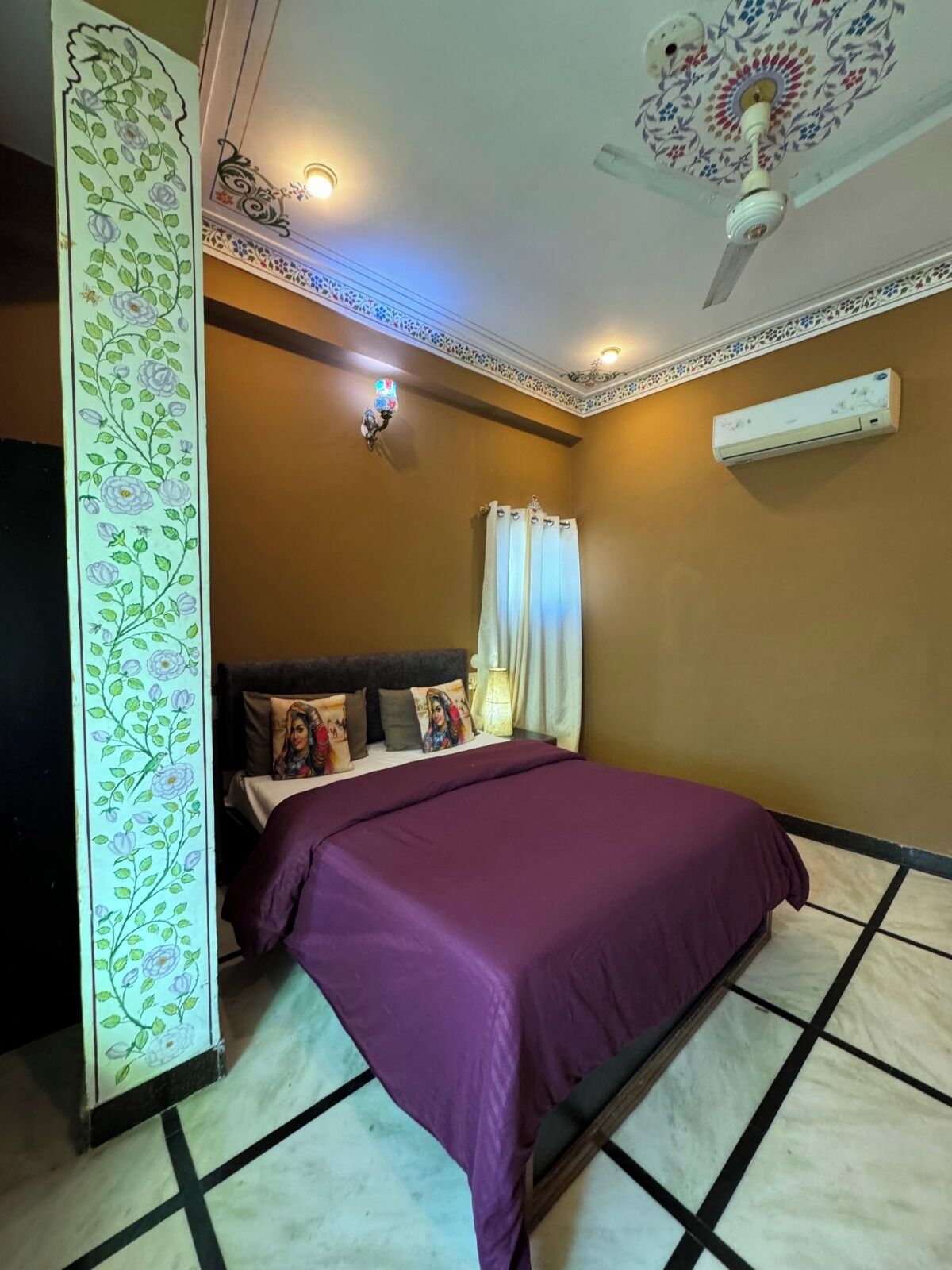 Un dormitorio con cama, ventilador de techo, equipo de aire acondicionado y un panel decorativo en la pared.