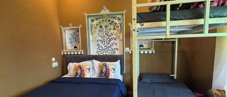 A dormitory room with two bunk beds, a decorative wall panel, and a small bedside table.