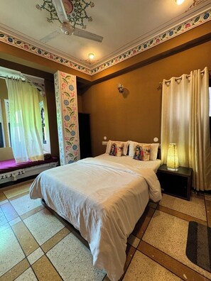 A bedroom with a bed, a nightstand, a lamp, a window with curtains, and a decorative ceiling. - Mild Life Hostel Udaipur (Udaipur)