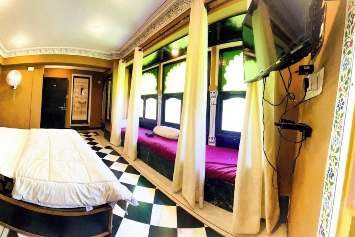 Una camera d'albergo con un letto grande, una televisione e una finestra con tende.
