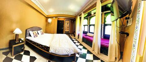 A hotel room with a large bed, a television, and a window with curtains.