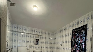 A bathroom with a toilet, sink, and shower. The walls have a patterned tile design. - Mild Life Hostel Udaipur (Udaipur)