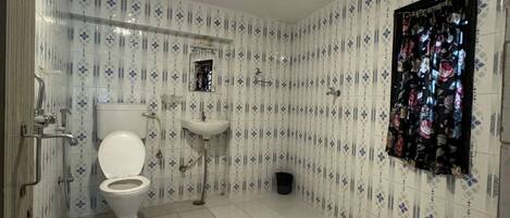 A bathroom with a toilet, sink, and shower. The walls have a patterned tile design.