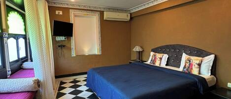 Habitación de hotel con piso a cuadros, cama con cubrecama azul, televisor de pantalla plana montado en la pared y aire acondicionado.