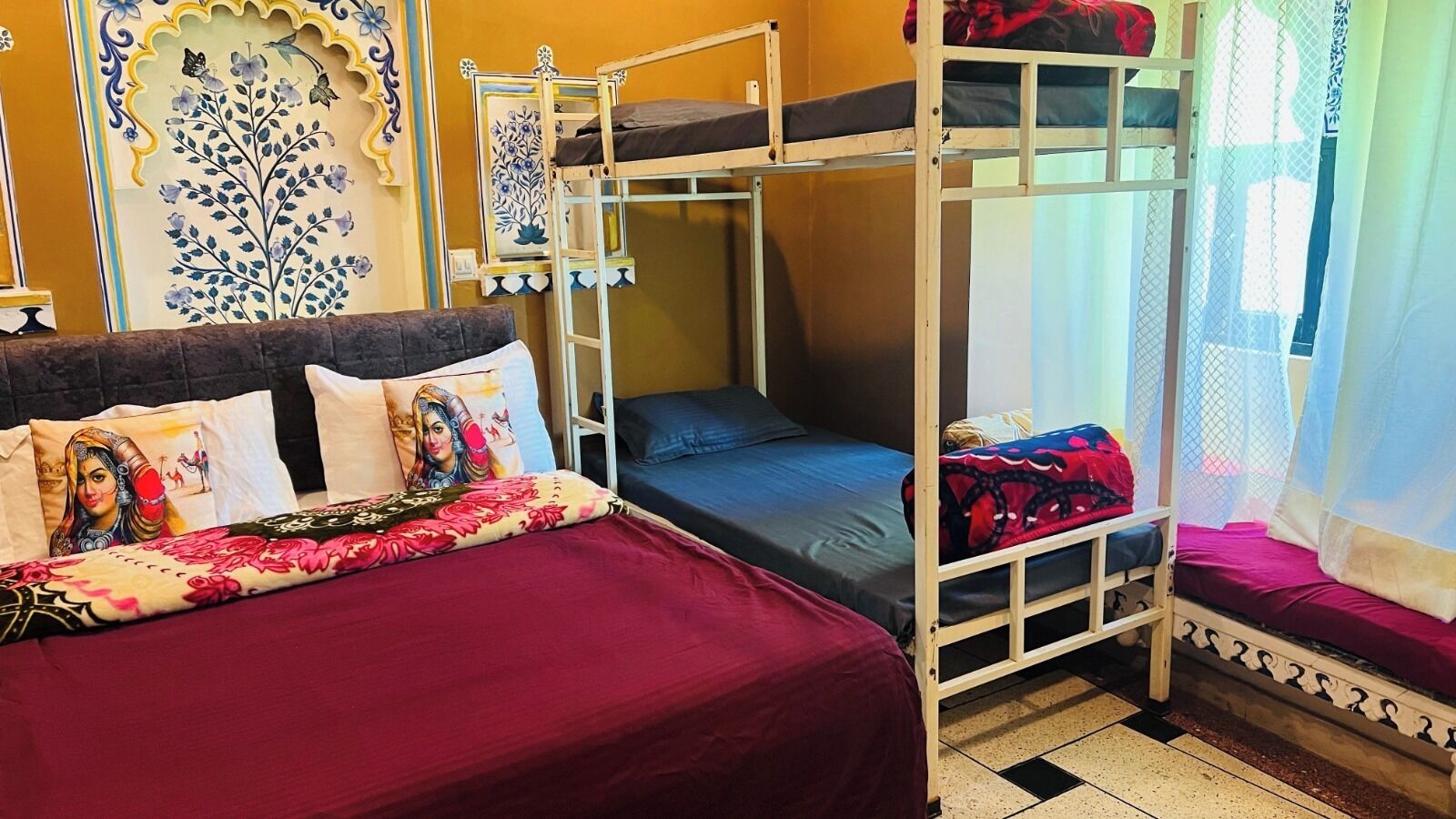 A bunk bed room with a floral bedspread, a decorative wall piece, and a mosquito net over the upper bunk.