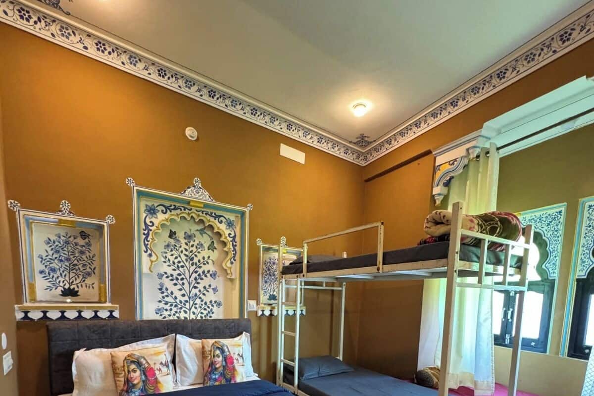 Una stanza con un letto grande, due letti a castello, pannelli decorativi e una finestra con tende.
