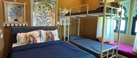 A room with a large bed, two bunk beds, decorative wall panels, and a window with curtains.