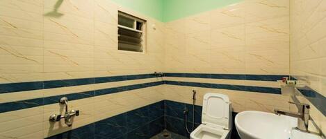 A bathroom with a toilet, bidet, and sink, featuring a striped tile design.