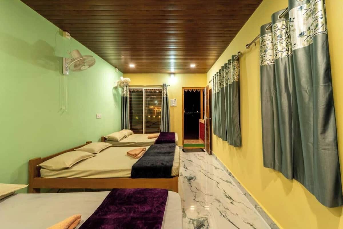 Hotellihuone, jossa on kaksi sänkyä, kattotuuletin ja näkymä ulos.