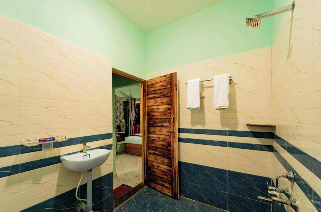 A bathroom with a wooden door, a sink, and a shower area.