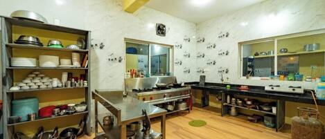 Una cocina con electrodomésticos de acero inoxidable, estantes de madera con vajilla y una cocina grande.