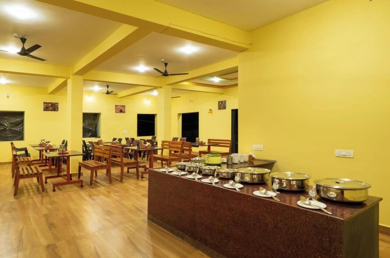 Un comedor con varias mesas y sillas, un mostrador de buffet con diferentes recipientes de comida y ventiladores de techo.